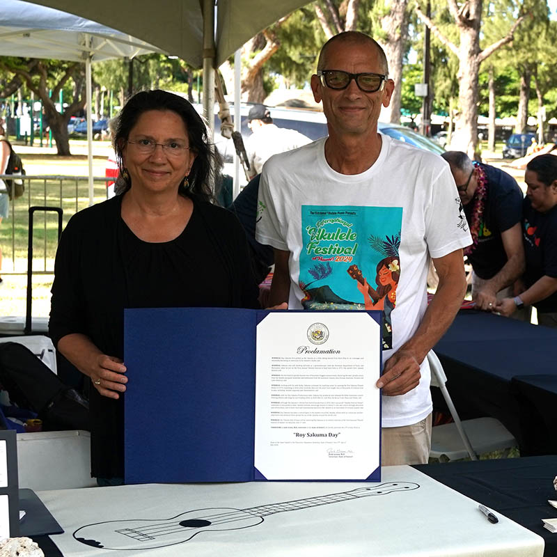 ʻUkulele Hall of Fame directors Nuni Walsh and Paul Syphers with the Governor's Proclamation designating July 27th, 2024 Roy Sakuma Day